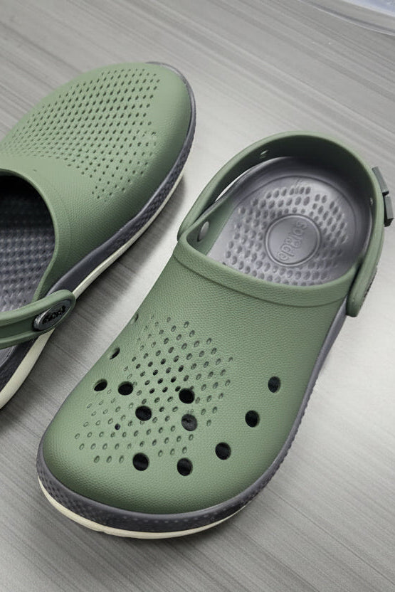 Green and gray sandals with a visible brand logo on a metallic surface