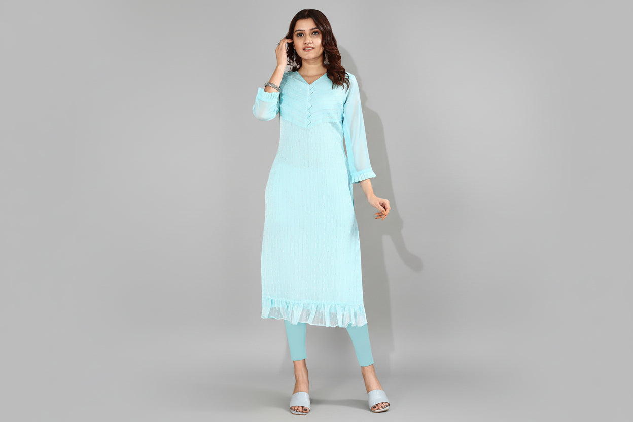 Woman wearing a light blue kurta with a beige background and a decorative vase.